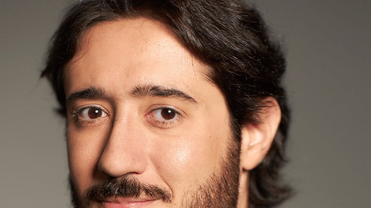 Retrato de Gabriel Azevedo, de terno escuro e gravata vermelha, olhando para a câmera