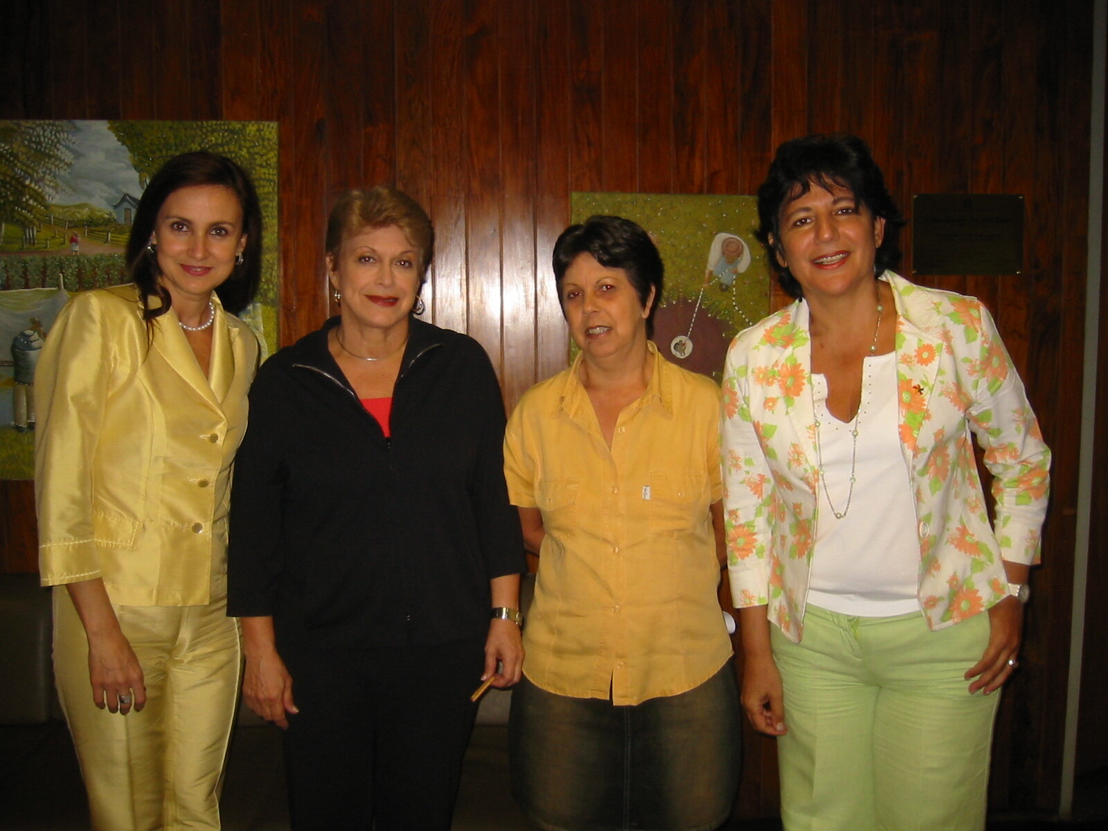 Quatro mulheres posam lado a lado diante de parede de madeira na Assembleia Legislativa de São Paulo