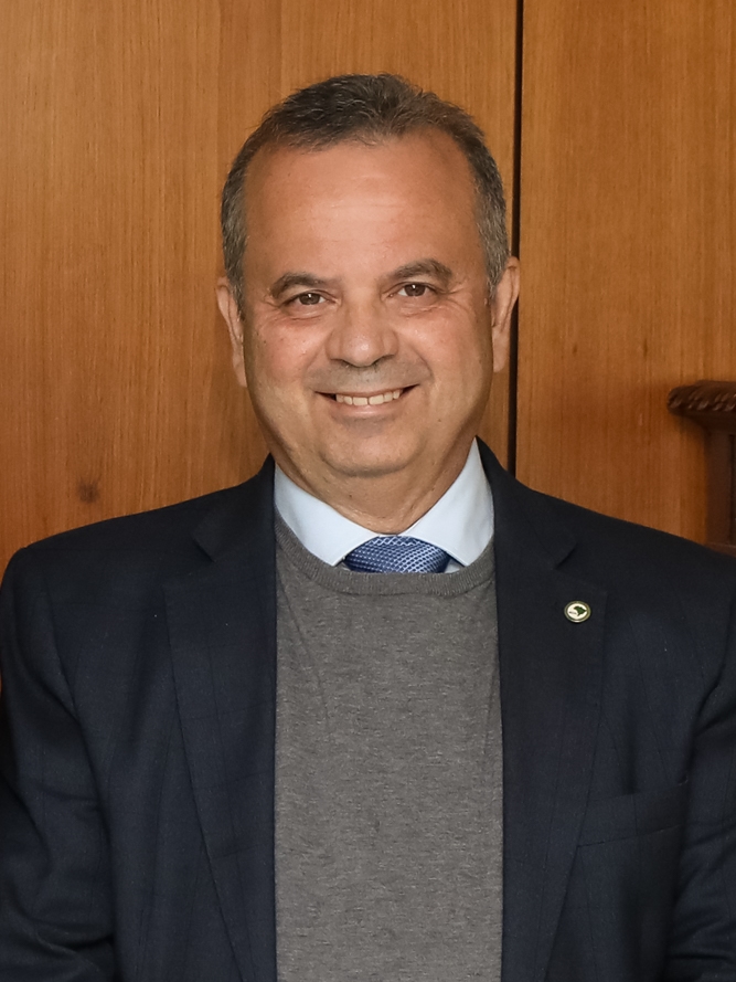 Rogério Marinho, de paletó escuro e suéter cinza, sorri em plano médio