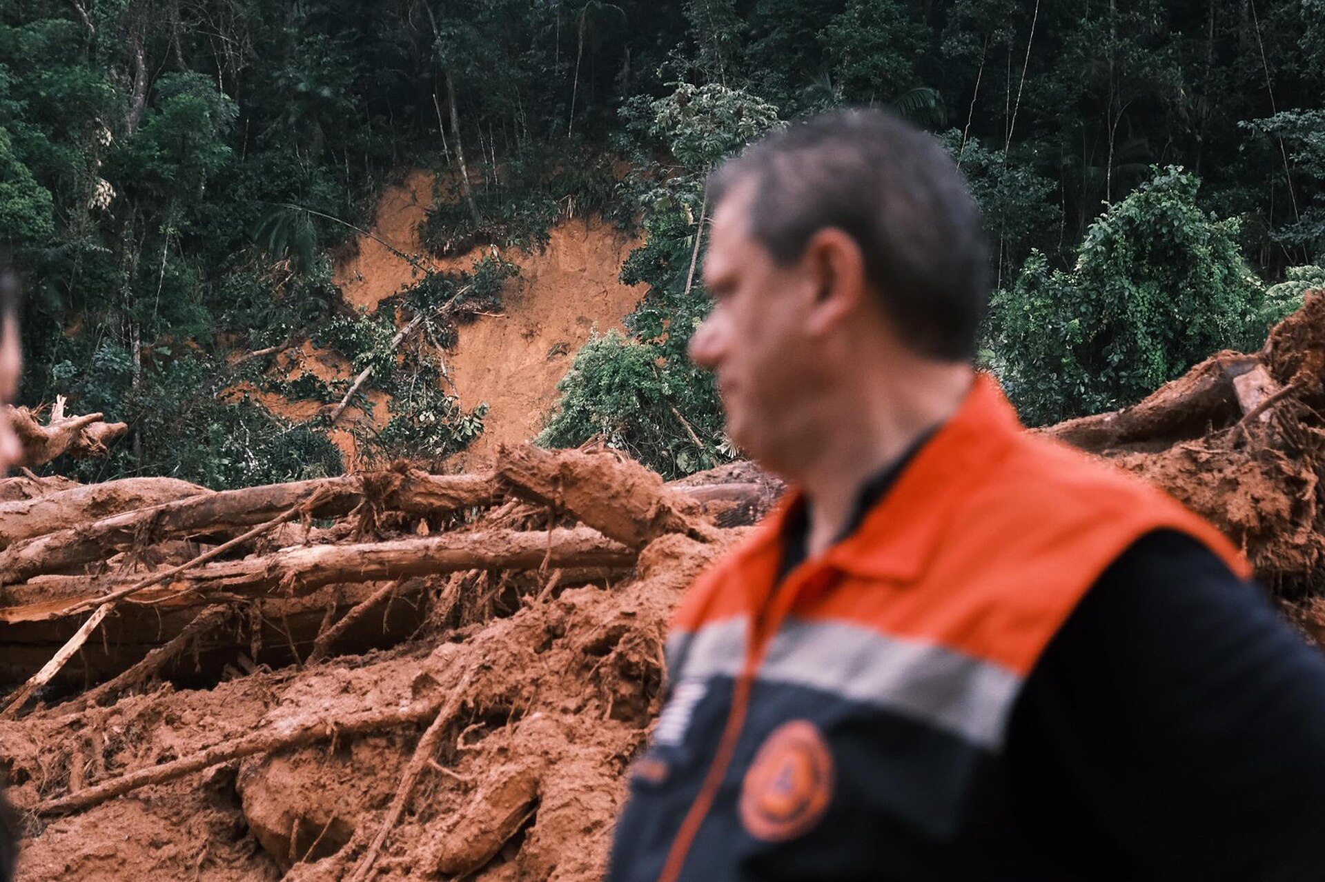 Tarcísio de Freitas, de colete laranja da Defesa Civil, observa área atingida por deslizamento de terra