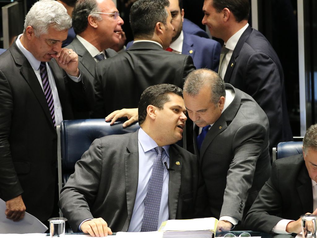 Davi Alcolumbre, sentado à Mesa do Senado, conversa com Rogério Marinho, que se inclina ao seu lado