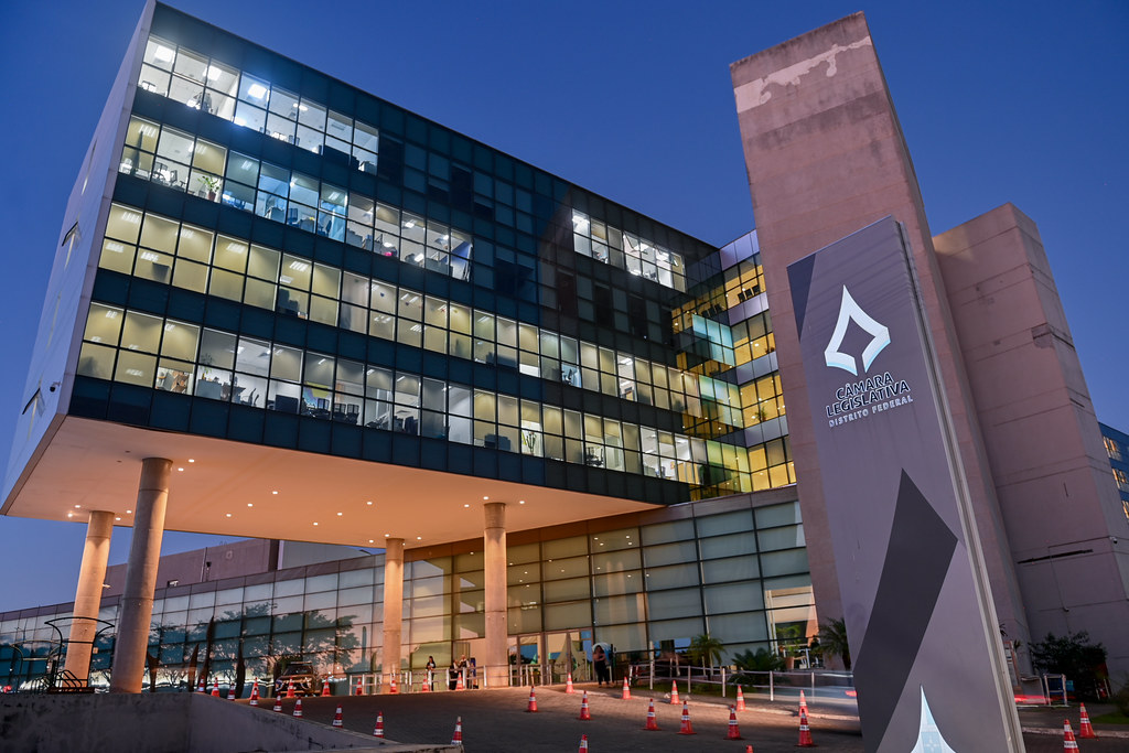 Fachada da Câmara Legislativa do Distrito Federal, com edifício envidraçado iluminado e identificação da CLDF à direita