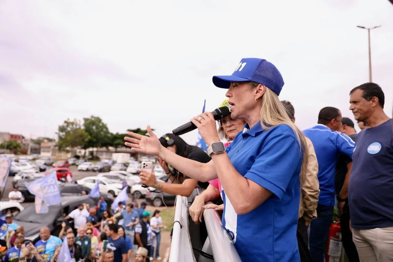 Celina Leão, de boné e camisa azuis com o número 11, discursa ao microfone para apoiadores durante carreata da campanha